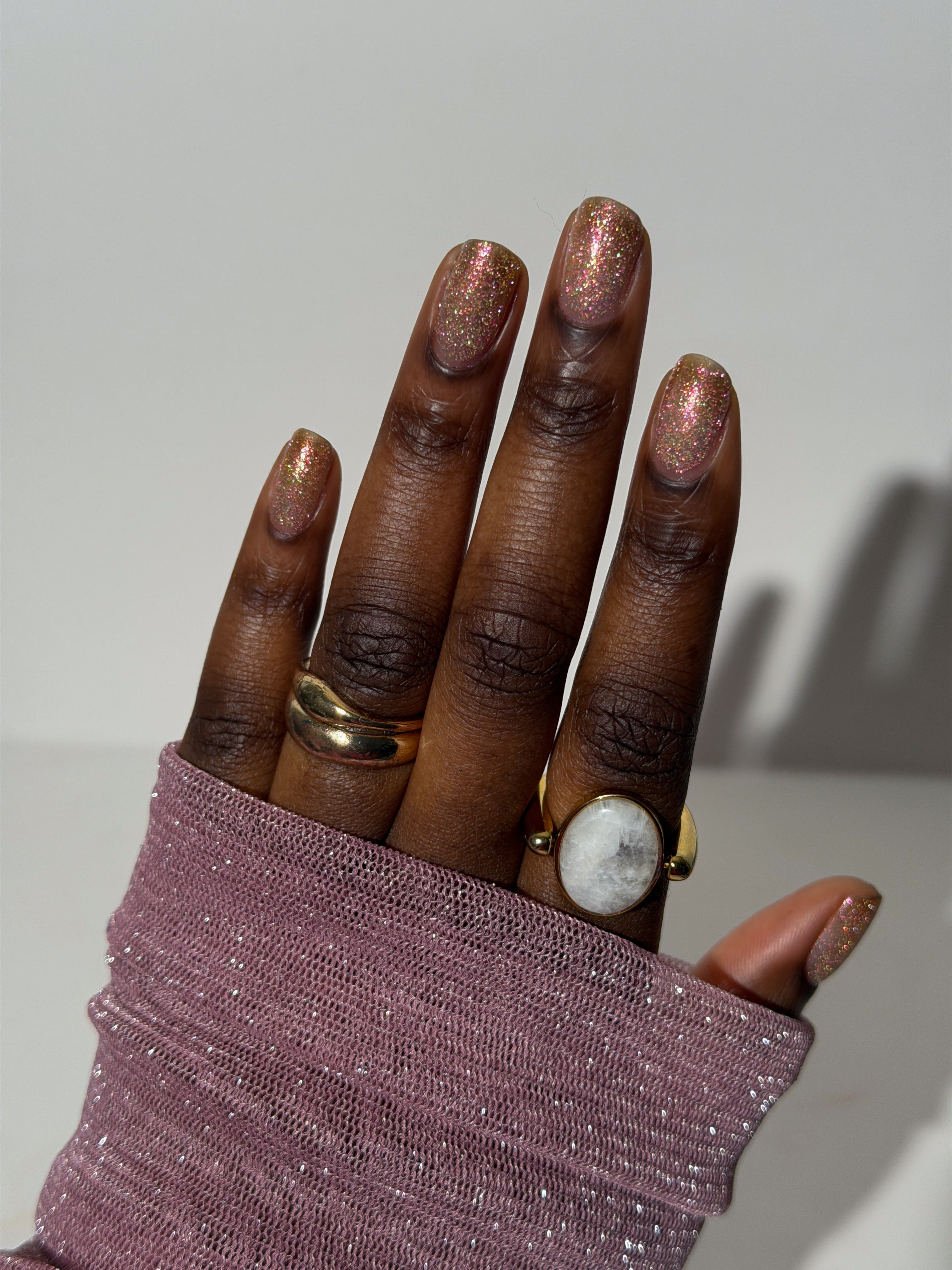 Resistance by Glitch Lacquer, peach-gold reflective glitter swatch on deep skin, oval nails