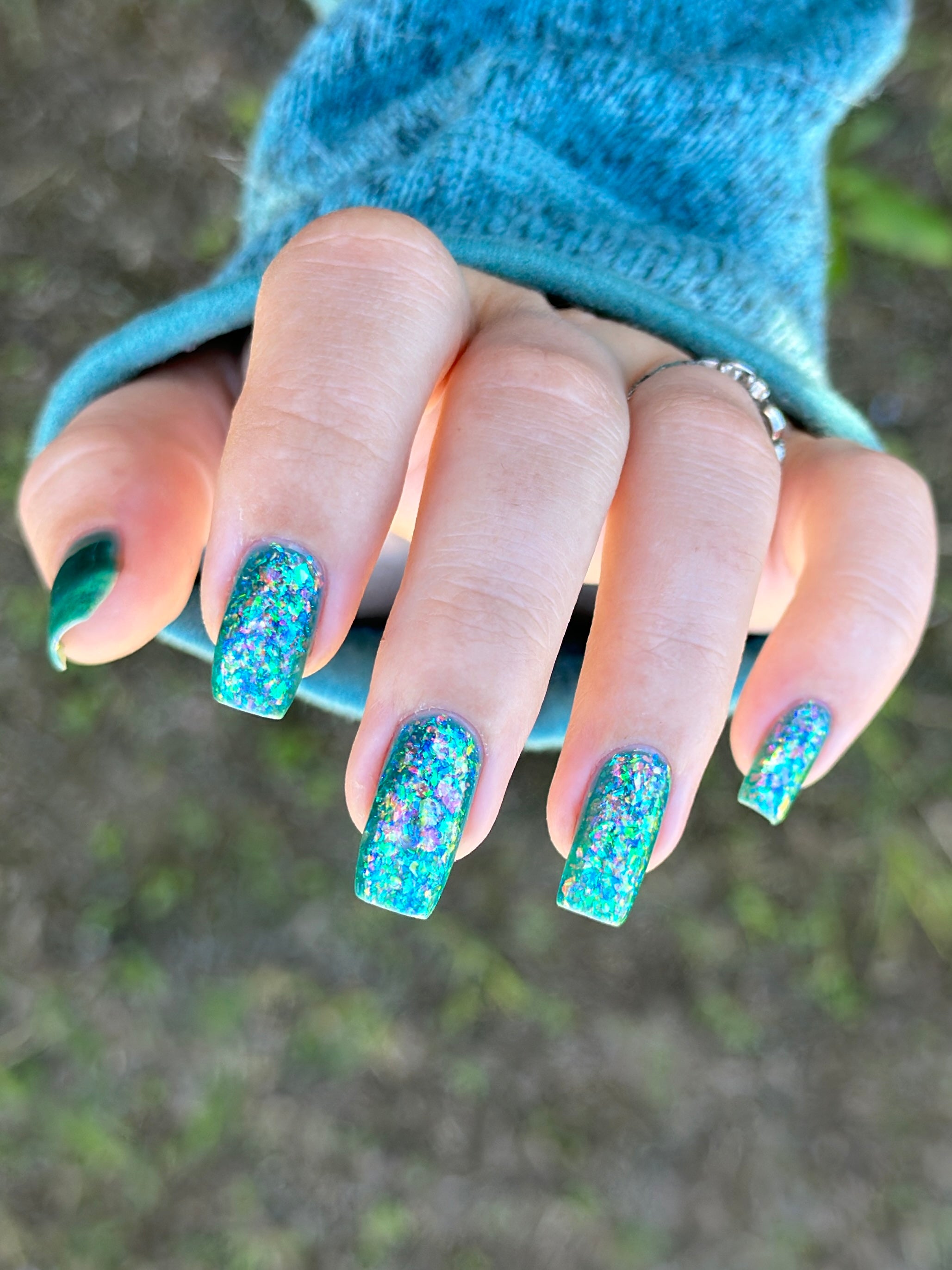 Medo by Glitch Lacquer, teal jelly with iridescent flakies on light skin, long squoval nails