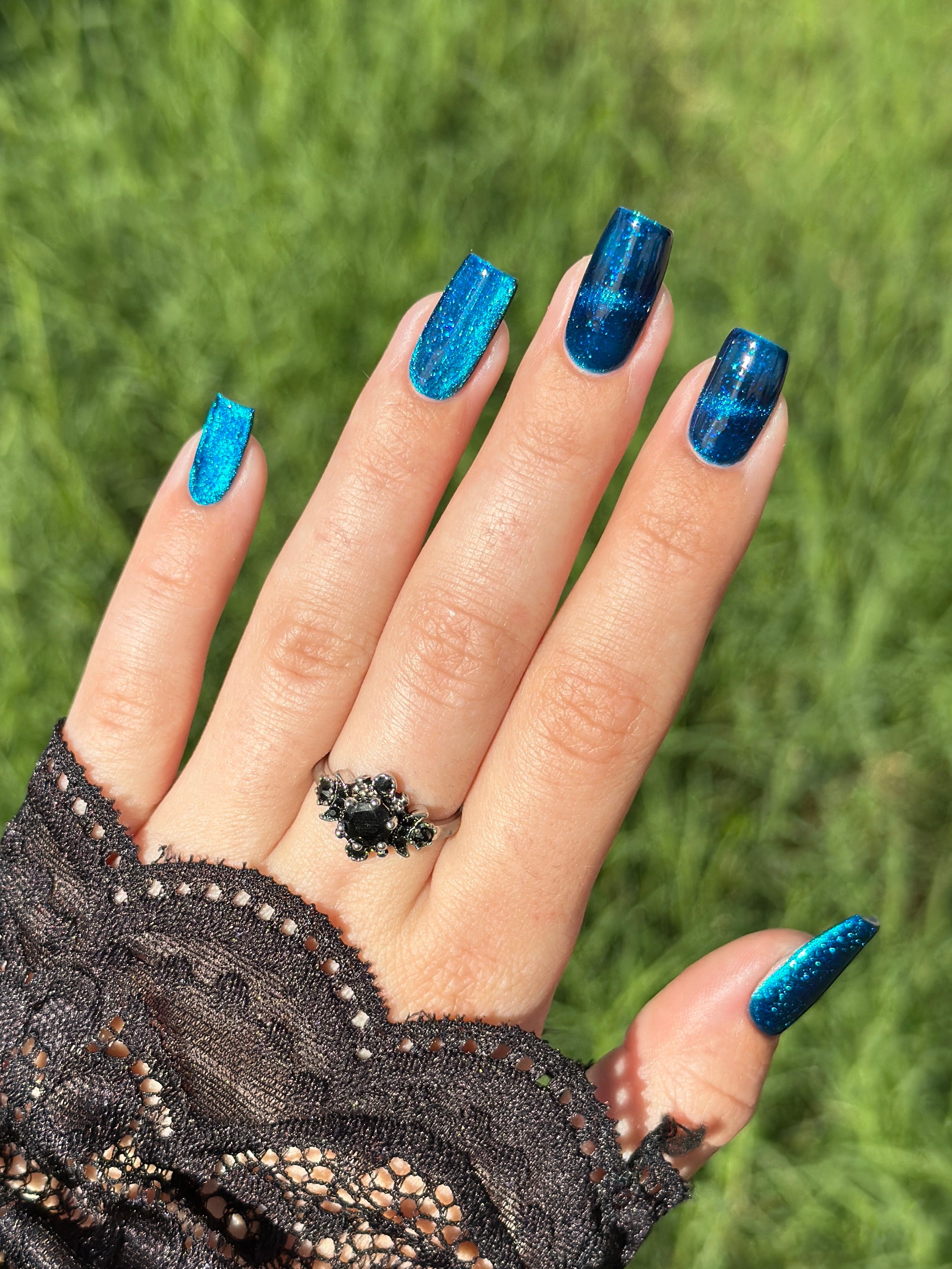 Heart of the Ocean by Glitch Lacquer on five long coffin nails, deep blue magnetic jelly with strong magnetic line and blue glitters, light-medium skin tone, bright daylight.