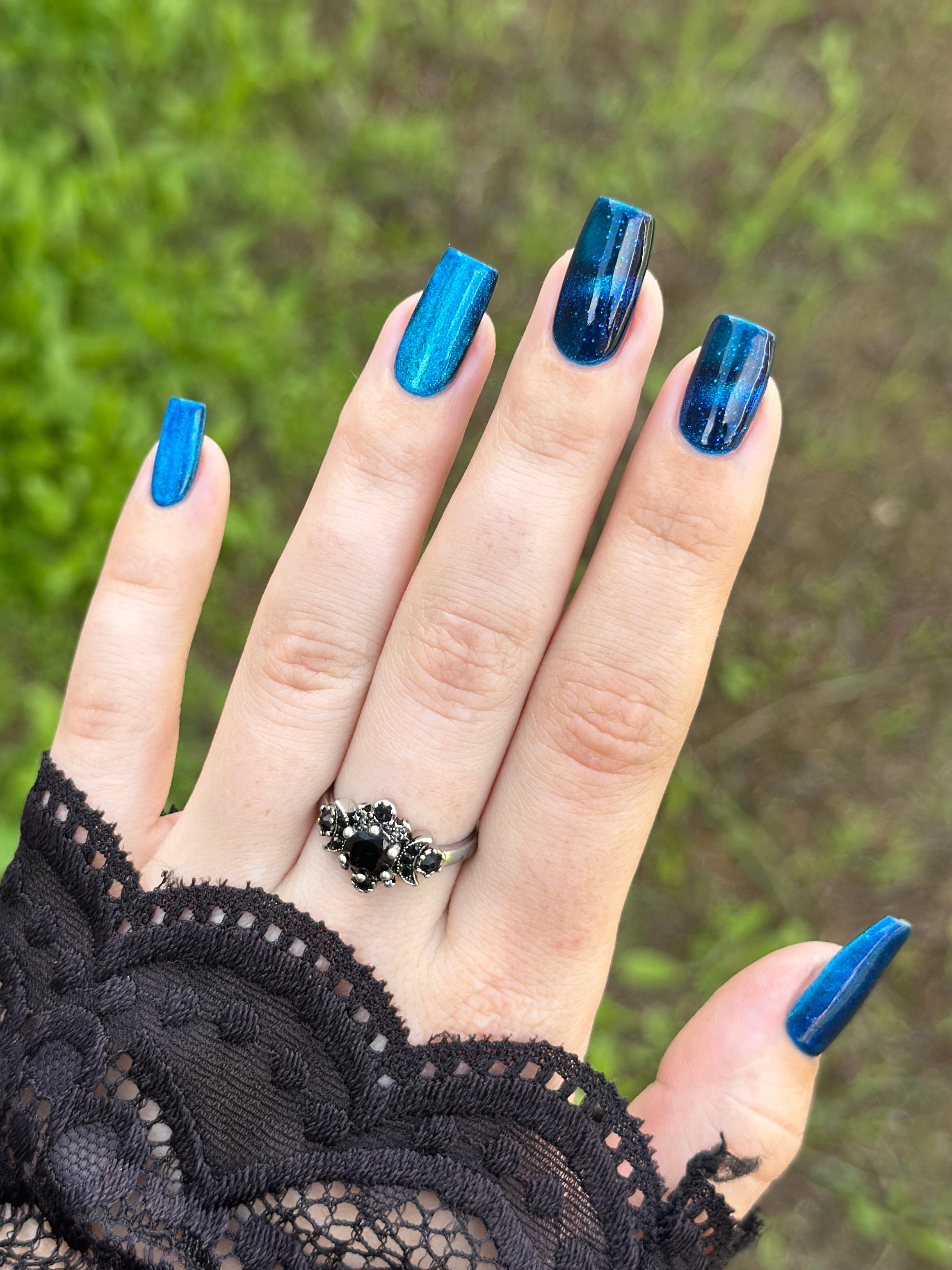 Heart of the Ocean by Glitch Lacquer on five coffin nails worn with a black lace glove, deep blue magnetic jelly with blue glitters, light-medium skin tone, bright daylight.