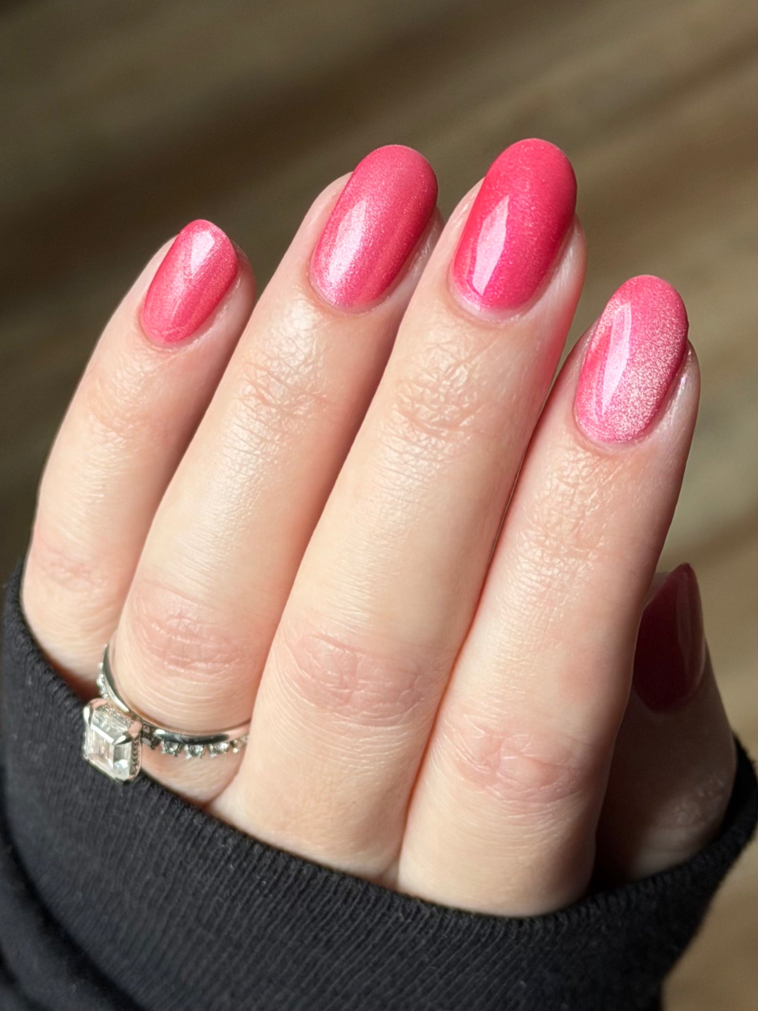 Lovey Dovey by Glitch Lacquer on five oval nails, warm pink polish with pink-to-gold reflective shimmer and silver magnetic pigment, light skin tone, bright daylight.