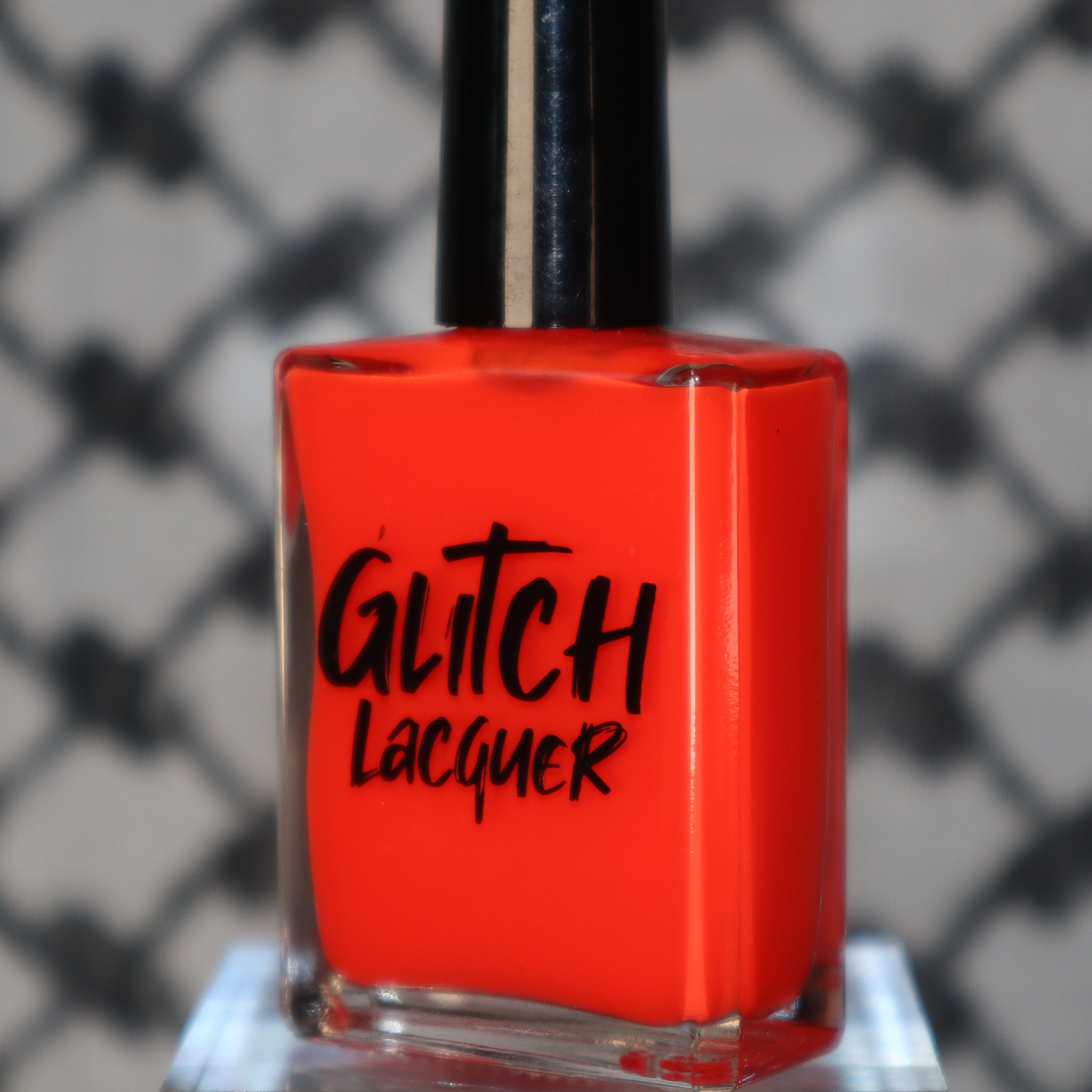 Palestinian Poppy by Glitch Lacquer, warm red crelly bottle shot on a keffiyeh-patterned background