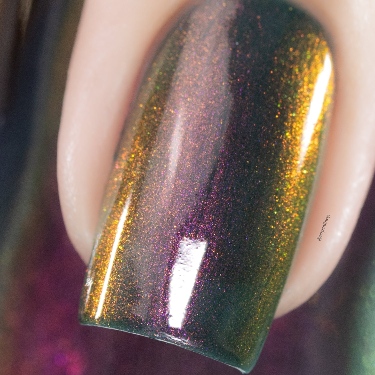 Holographic multichrome shimmer Cadillacquer nail polish in Fear What You Will Become, extreme closeup macro swatch on a single square nail showing a deep murky teal-green base shifting through dark olive-gold and bronze, with dense magenta-to-amber-orange holographic shimmer flash, light skin tone, studio lighting, swatched by @serpentine13