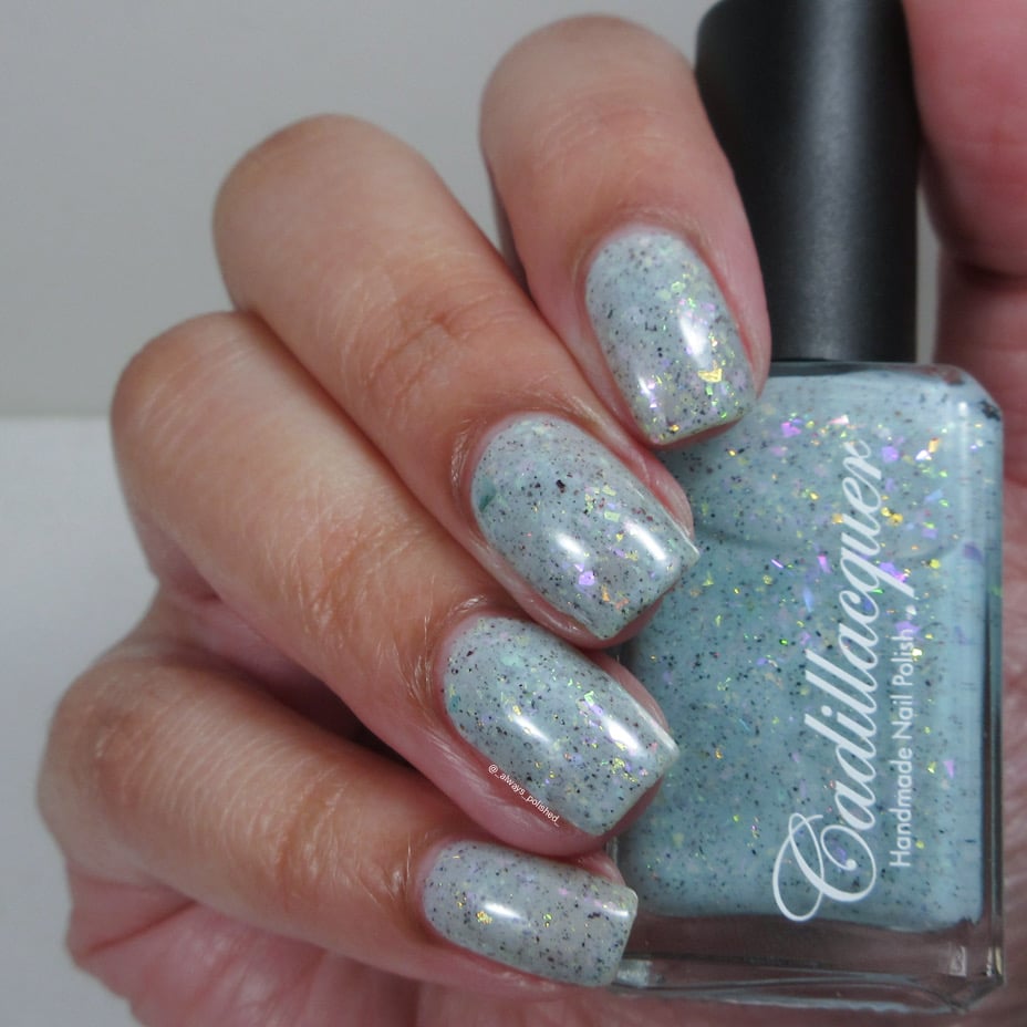 Cadillacquer Fresh Sheets pastel mint iridescent crelly nail polish, bottle held with four-nail swatch, light skin, studio lighting