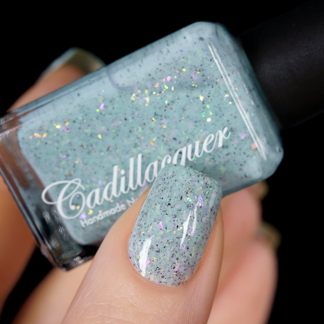 Cadillacquer Fresh Sheets pastel mint iridescent crelly nail polish, bottle held with one-nail swatch, light skin, studio lighting