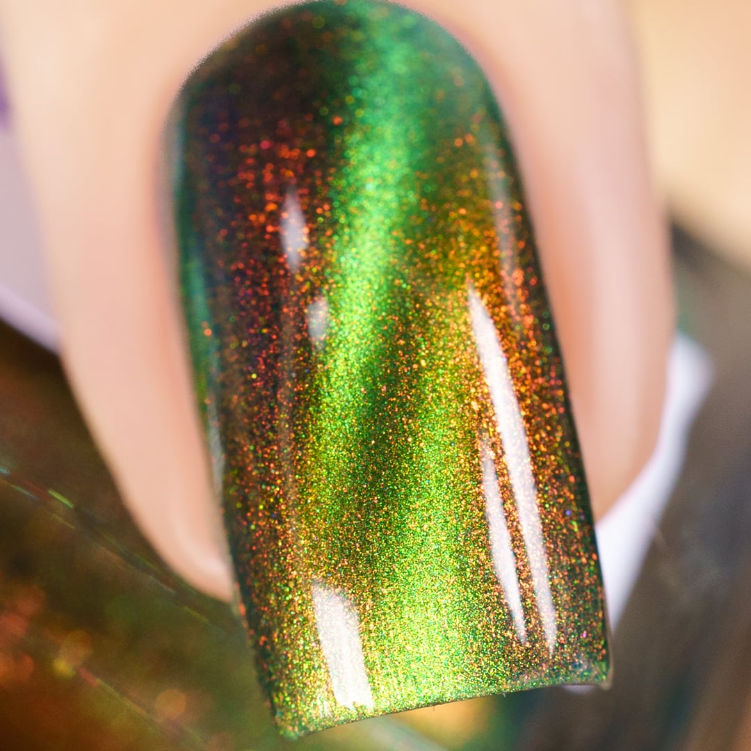 Multichrome magnetic shimmer Cadillacquer nail polish in I Found A Place, extreme close-up swatch on a single oval nail showing a bright lime-green magnetic cat-eye band over a deep forest-green sheer base, packed with red-to-amber aurora shimmer particles that shift across the surface, light skin tone, studio lighting, swatched by @yyulia_m