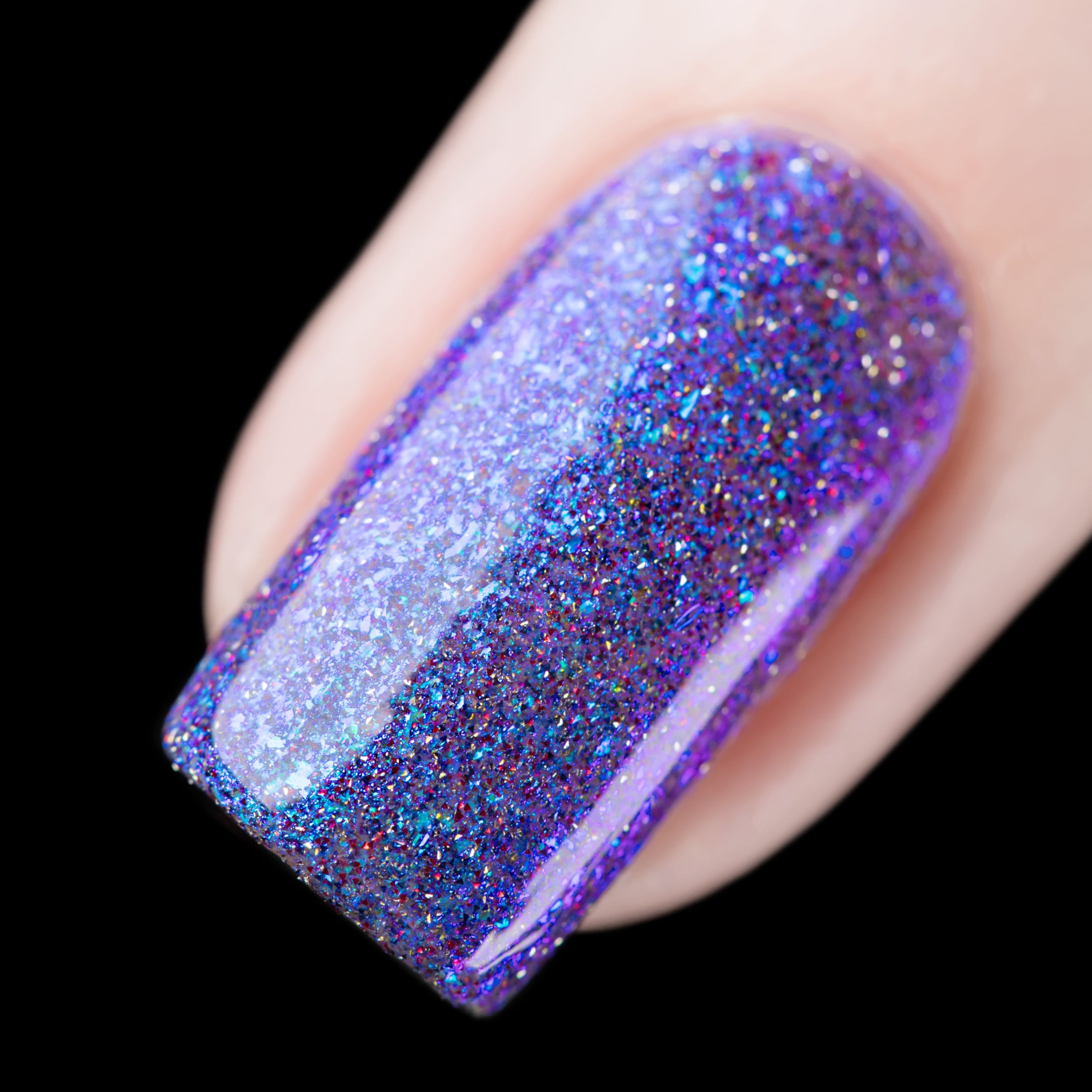Flaky shimmer and reflective glitter Cadillacquer nail polish in I'll Be Right Back, single square nail swatch showing a sheer purple-violet base densely packed with iridescent blue micro flakes, cyan-blue shimmer, and red and charcoal reflective micro glitter, light skin tone, studio lighting, swatched by @rafinails