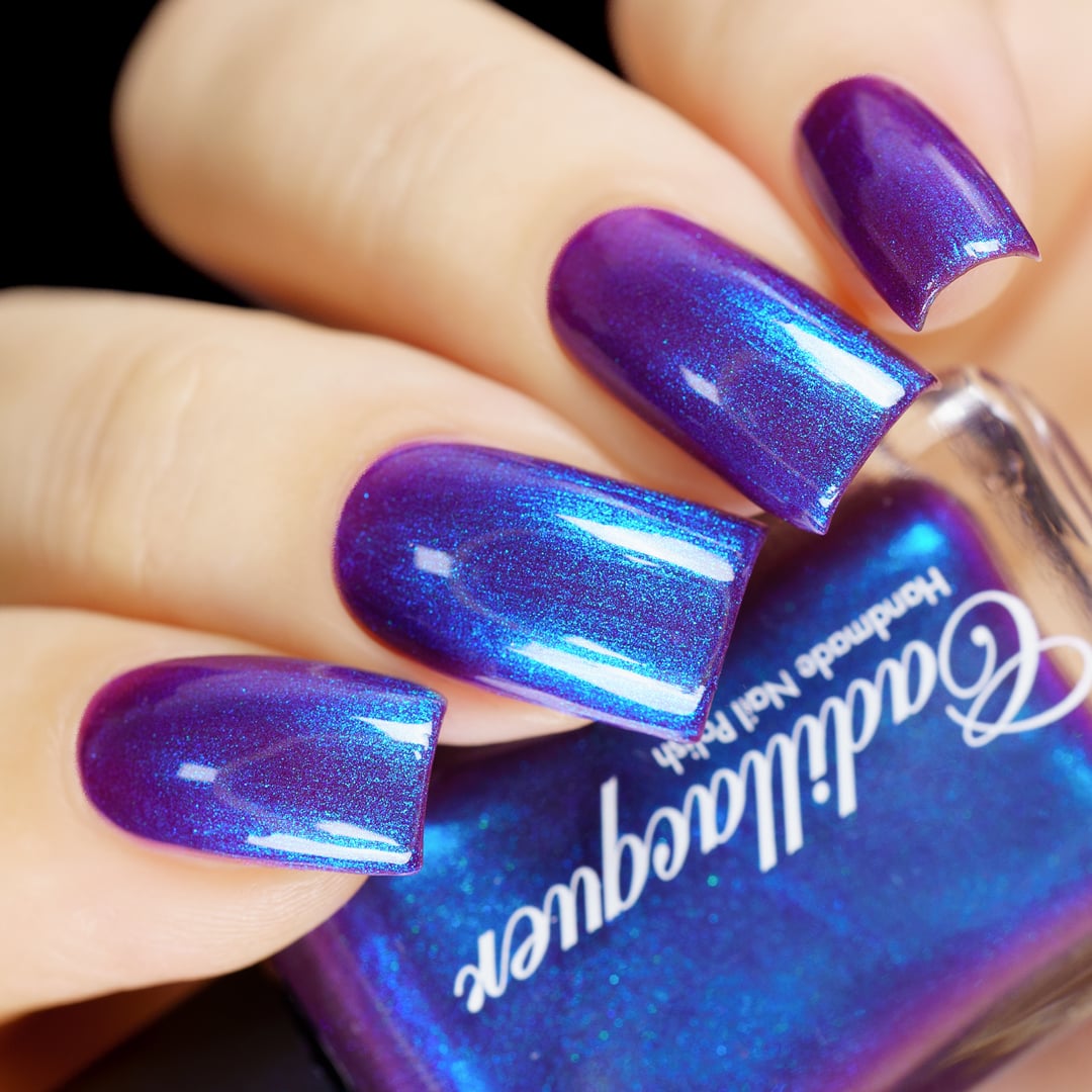 Multichrome shimmer Cadillacquer nail polish in Keep Doubting, swatched on four squoval nails held alongside the bottle, shifting from deep mulberry-violet at face-on angles to vivid electric blue at oblique angles, with cyan-teal shimmer glints, light skin tone, studio lighting, swatched by @yyulia_m
