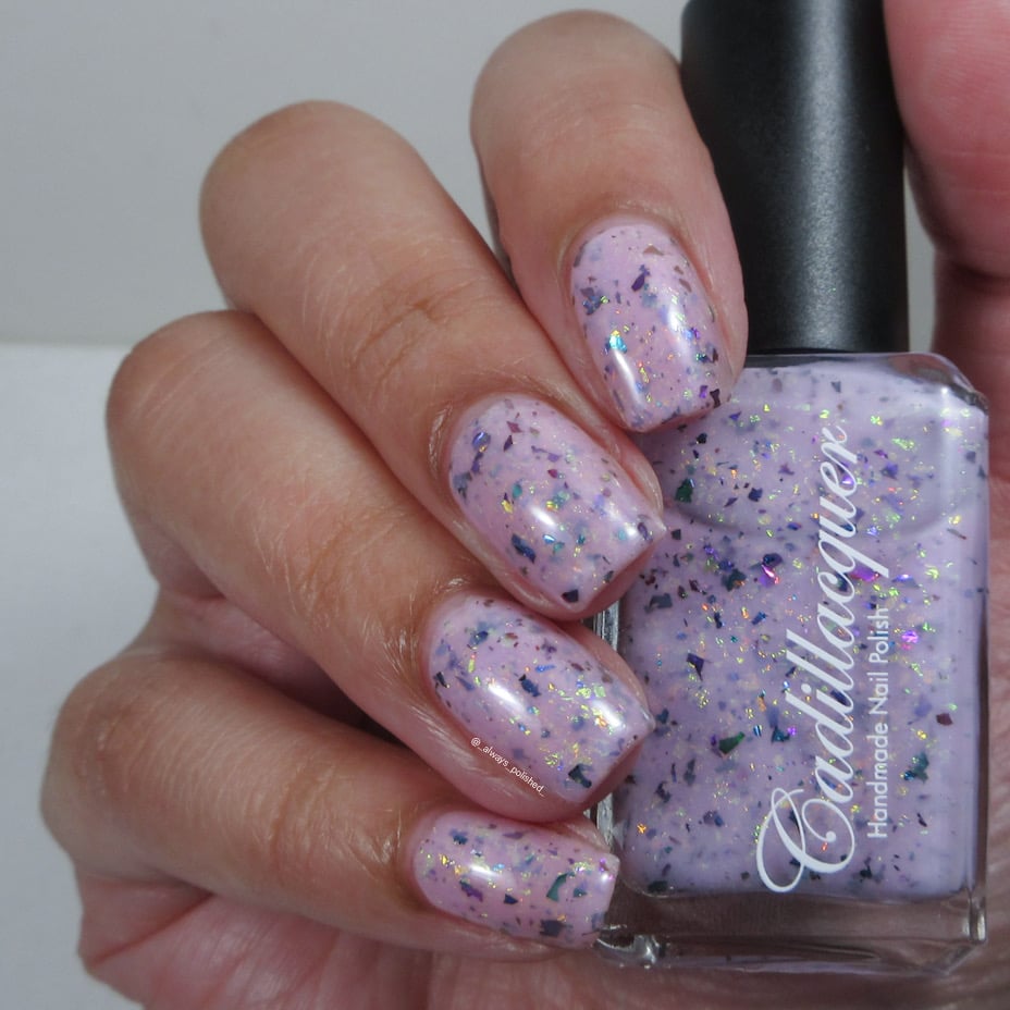 Cadillacquer Sweet Nothing pink teal chameleon iridescent crelly nail polish, bottle held with four-nail swatch, light skin, studio lighting