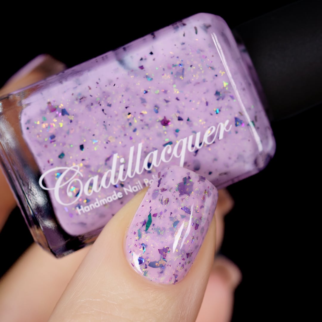 Cadillacquer Sweet Nothing pink teal chameleon iridescent crelly nail polish, bottle held with one-nail swatch, light skin, studio lighting
