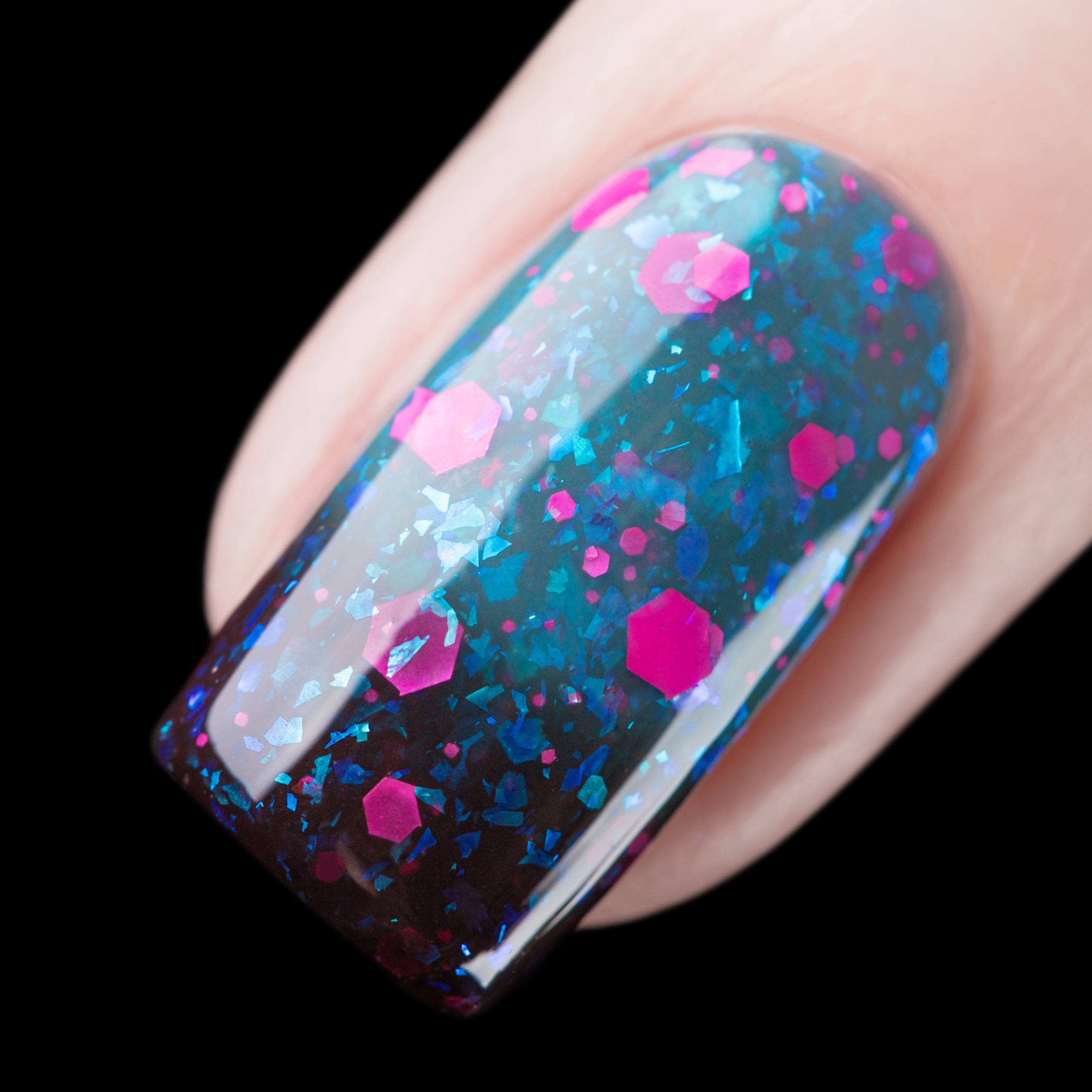 Thermal glitter and flake Cadillacquer nail polish in What Lurks Within, shown as a single macro swatch on one squoval nail, transitioning from very dark blackened teal at the cold lower nail through mid teal to a lighter blue-teal at the warm upper nail, densely packed with matte neon hot pink hexagonal glitter in mixed sizes and iridescent cyan-blue flakes throughout, on light skin tone, studio lighting against black background, swatched by @rafinails