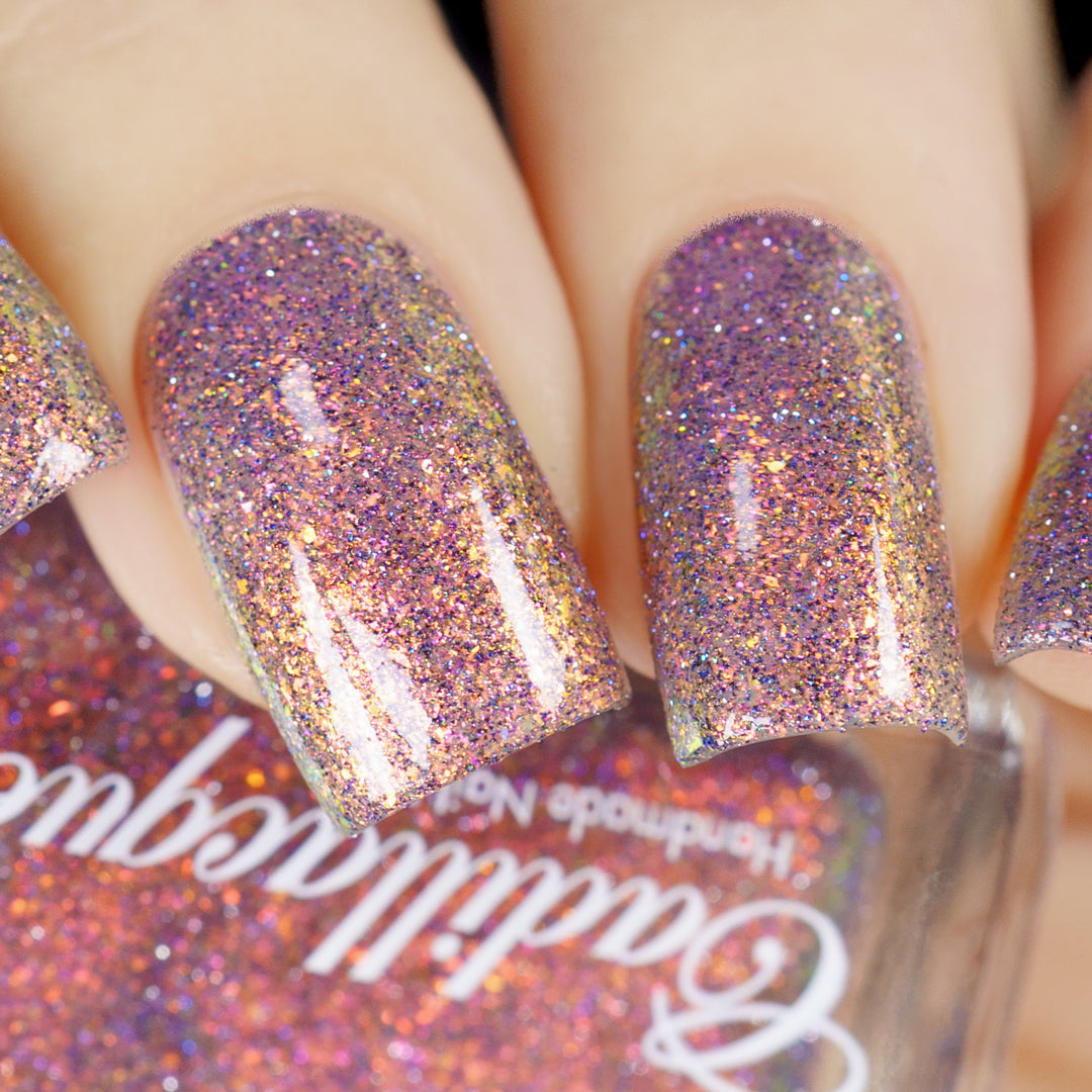 Multichrome flake and holographic glitter Cadillacquer nail polish in You Wished For This, swatched on five short square nails showing a dense scatter of iridescent micro flakes shifting from rosy mauve through gold-amber, red-orange, and violet with scattered silver and blue holographic glitter particles, on light skin tone, under direct flash lighting, swatched by @yyulia_m