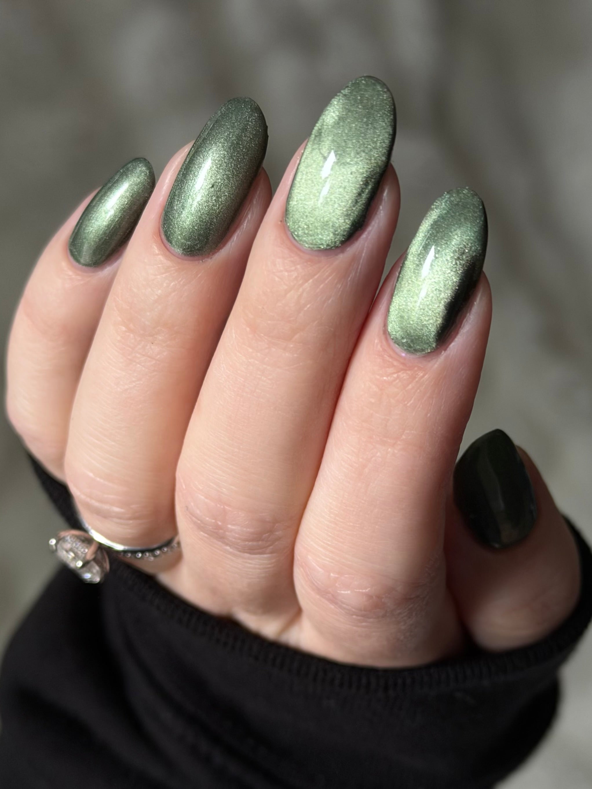 AUREA by Glitch Lacquer, blackened green base, greenish-gold magnetic cat-eye, on light skin tone almond nails