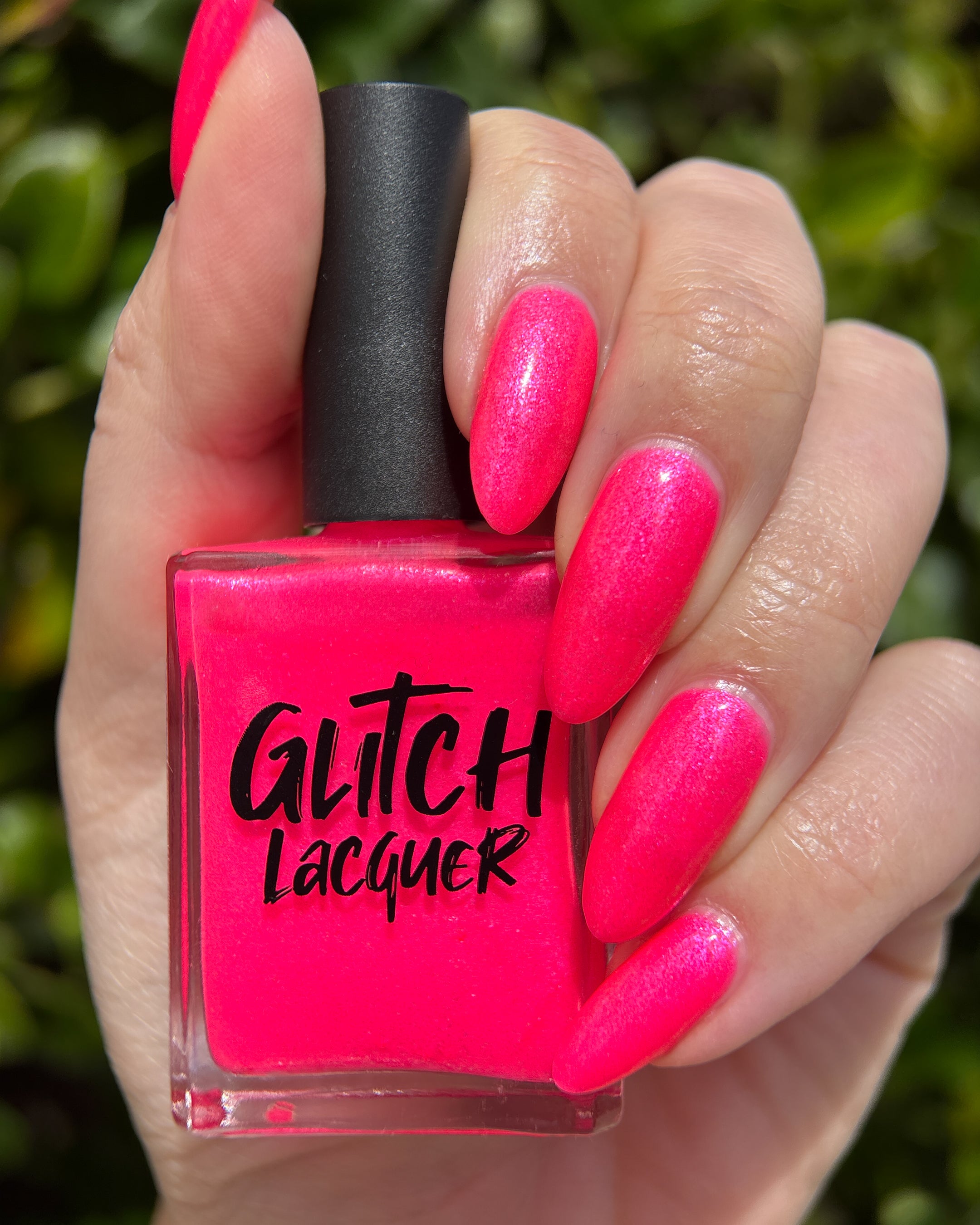 ACT UP by Glitch Lacquer, neon pink crelly with cool-toned pink sparkle, bottle in hand on light skin tone