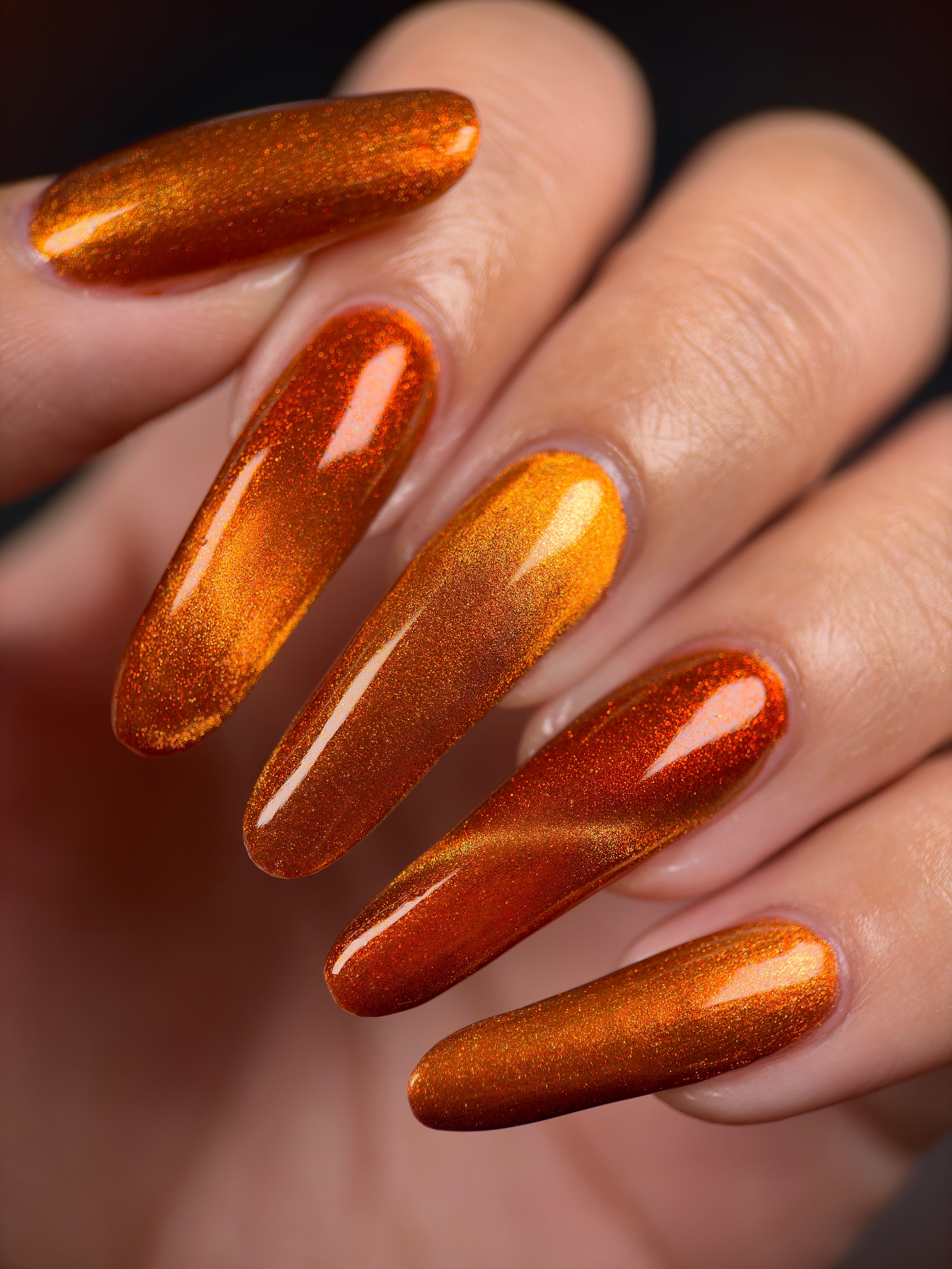 Marigold by Glitch Lacquer, burnt orange jelly, red shimmer, orange-to-gold magnetic, on light-medium skin tone almond nails