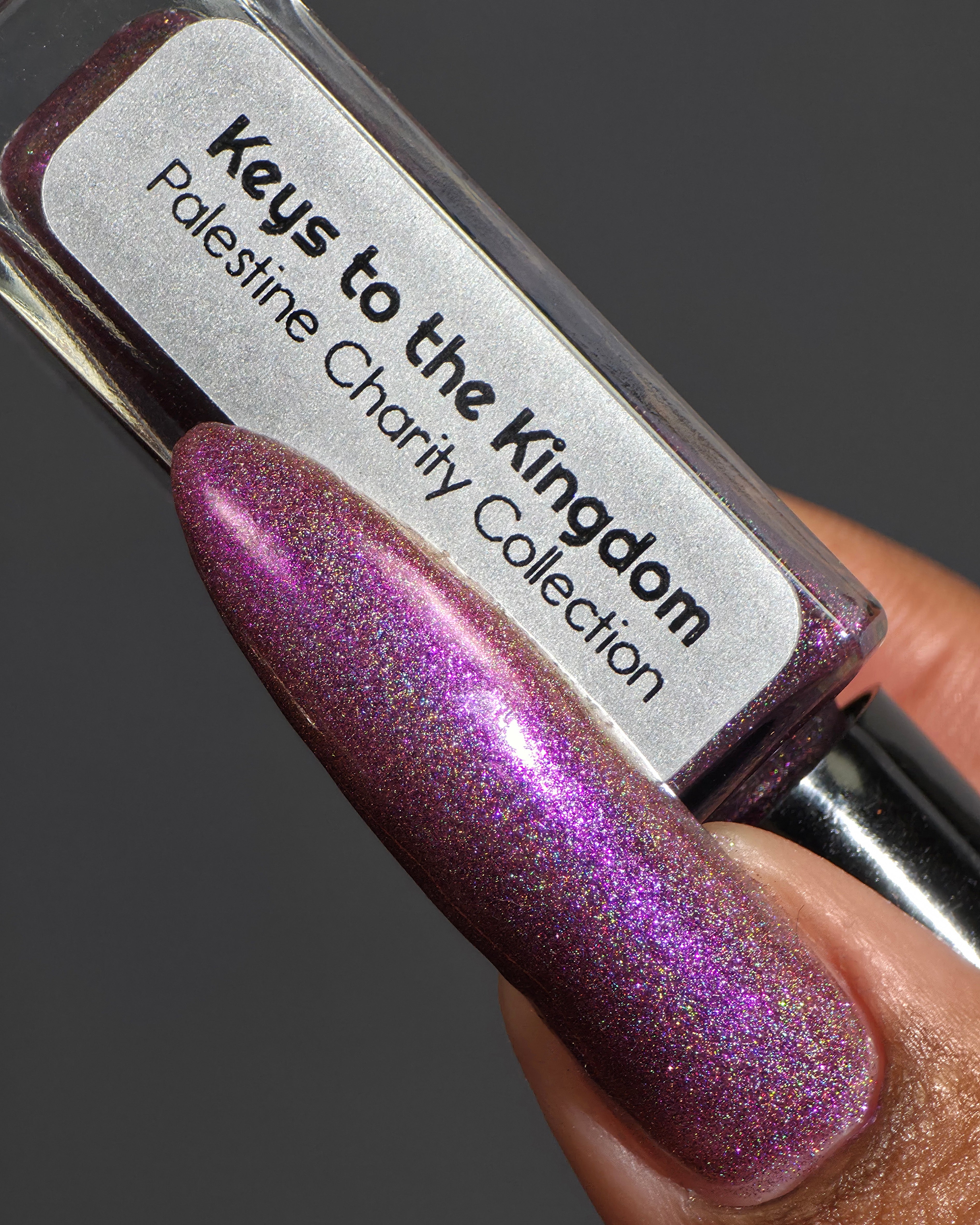 Keys to the Kingdom by Glitch Lacquer, berry multichrome holo bottle and swatch on rich skin tone