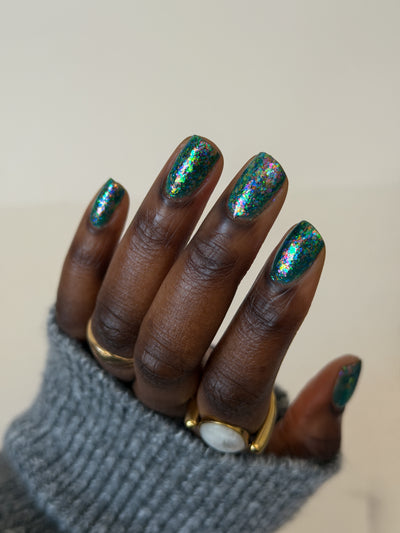 Medo by Glitch Lacquer, teal jelly with iridescent flakies swatch on rich skin, round nails
