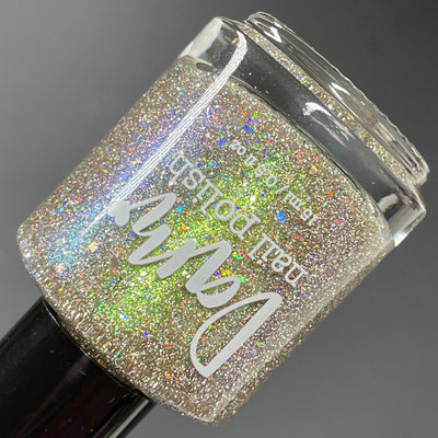 Thyme to Shine by Dam Nail Polish, green-to-purple shifting shimmer with silver holographic and reflective glitters under direct flash, bottle standalone product shot