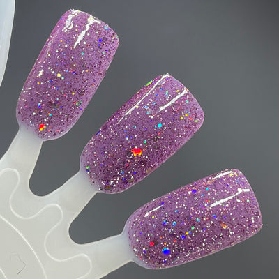 Thistle be the Day by Dam Nail Polish, warm purple jelly with fine silver holo micro-glitter and scattered larger holo flakes under direct flash, swatch stick