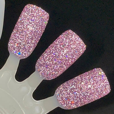 Thistle be the Day by Dam Nail Polish, warm mauve-purple jelly with mixed-size silver holographic glitters showing rainbow holographic flash under direct flash, swatch stick
