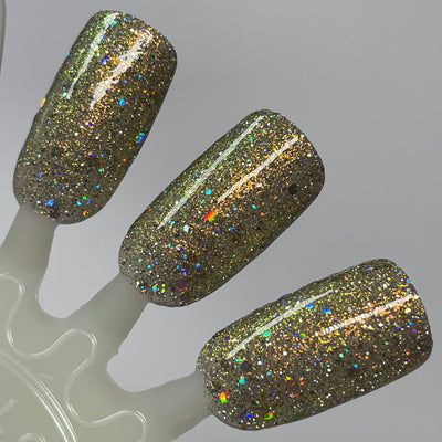 Sunny Side Up by Dam Nail Polish, olive-gold base with dense scattered hex and silver holo reflective glitter under direct flash, swatch stick