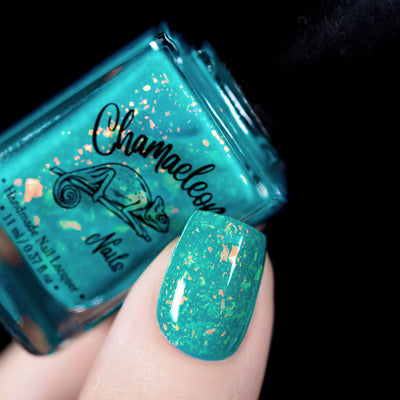 Kuang Si Falls by Chamaeleon Nails, neon teal jelly with large orange and yellow iridescent flakes flashing gold and green, bottle held in a light skin tone hand