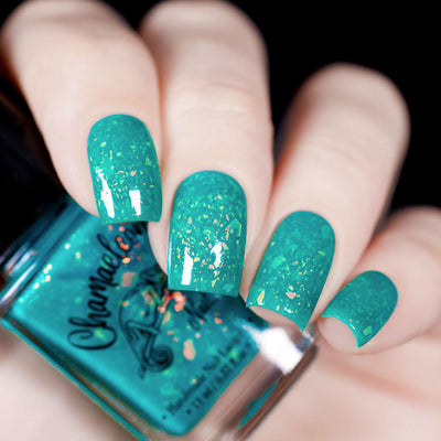 Kuang Si Falls by Chamaeleon Nails, neon teal jelly with large orange-to-gold multichrome iridescent flakies against dark background, on a light skin tone hand