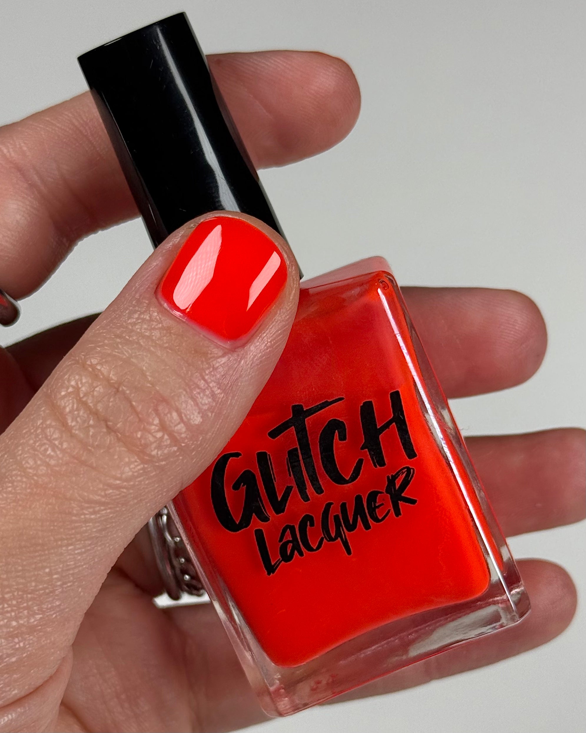 Palestinian Poppy by Glitch Lacquer, warm red crelly bottle in hand, light skin tone