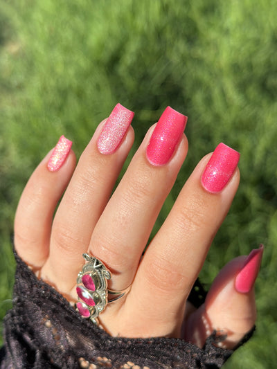 Lovey Dovey by Glitch Lacquer on five squoval nails, warm pink polish with pink-to-gold reflective shimmer and silver magnetic pigment, light-medium skin tone, bright daylight.