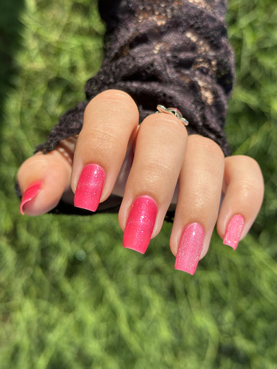 Lovey Dovey by Glitch Lacquer on five square nails, warm pink polish with pink-to-gold reflective shimmer, light-medium skin tone, bright daylight.