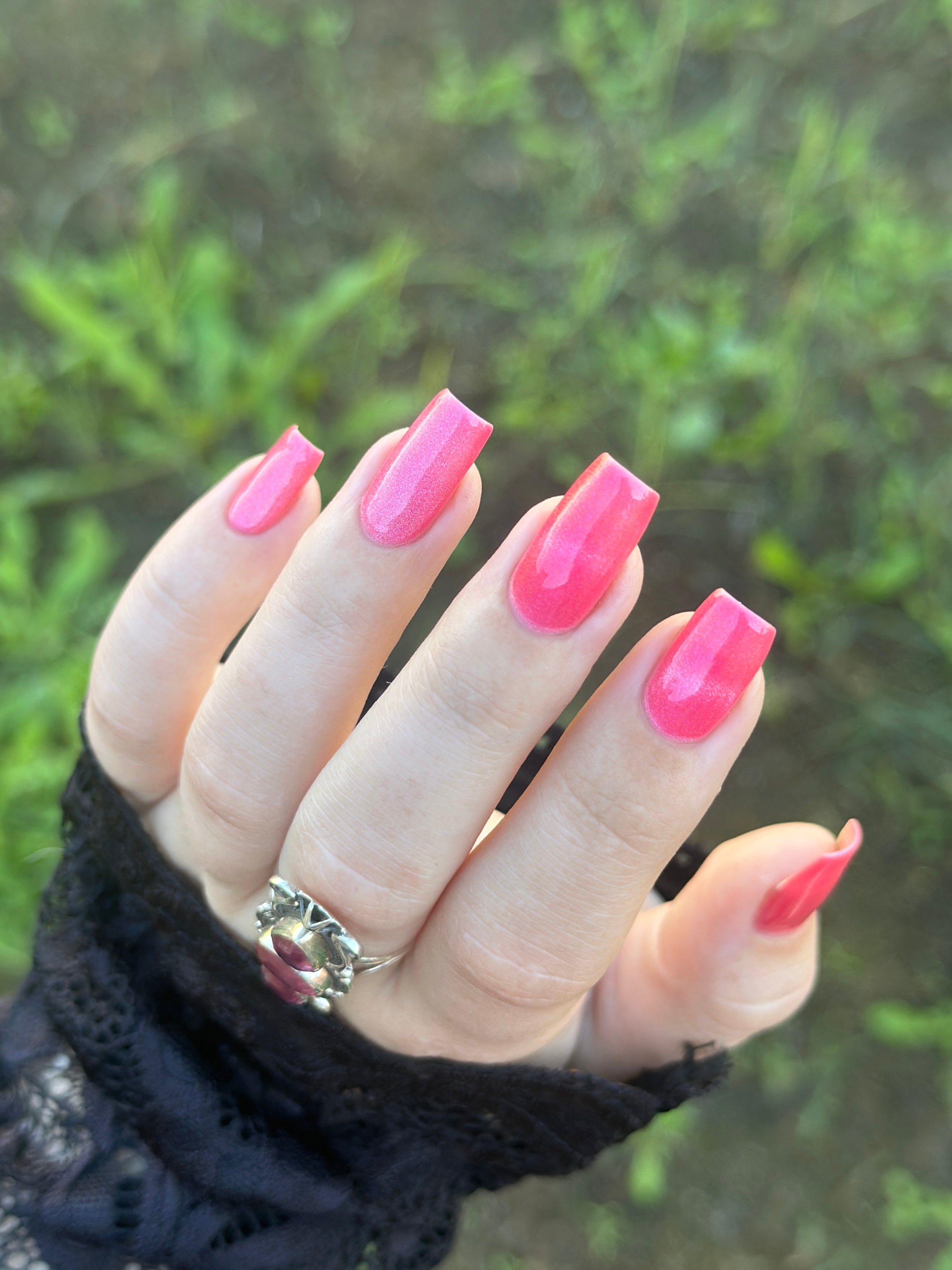 Lovey Dovey by Glitch Lacquer on five coffin nails, warm pink polish with pink-to-gold reflective shimmer and silver magnetic pigment, light skin tone, bright daylight.
