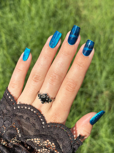 Heart of the Ocean by Glitch Lacquer on five long coffin nails, deep blue magnetic jelly with strong magnetic line and blue glitters, light-medium skin tone, bright daylight.
