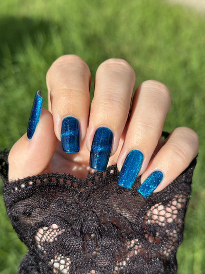 Heart of the Ocean by Glitch Lacquer on five long coffin nails worn with a black lace glove, deep blue magnetic jelly with blue glitters, light-medium skin tone, bright daylight.