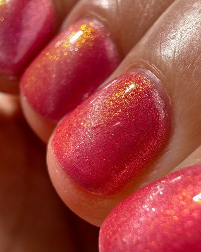Lovey Dovey by Glitch Lacquer macro detail on four nails showing the silver magnetic line, warm pink polish with strong pink-to-gold reflective shimmer, light-medium skin tone, bright daylight.