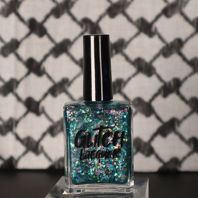 Medo by Glitch Lacquer, teal jelly with iridescent flakies bottle on keffiyeh-patterned background