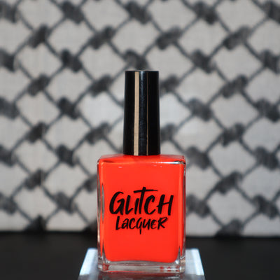Palestinian Poppy by Glitch Lacquer, warm red crelly bottle against a keffiyeh-patterned background