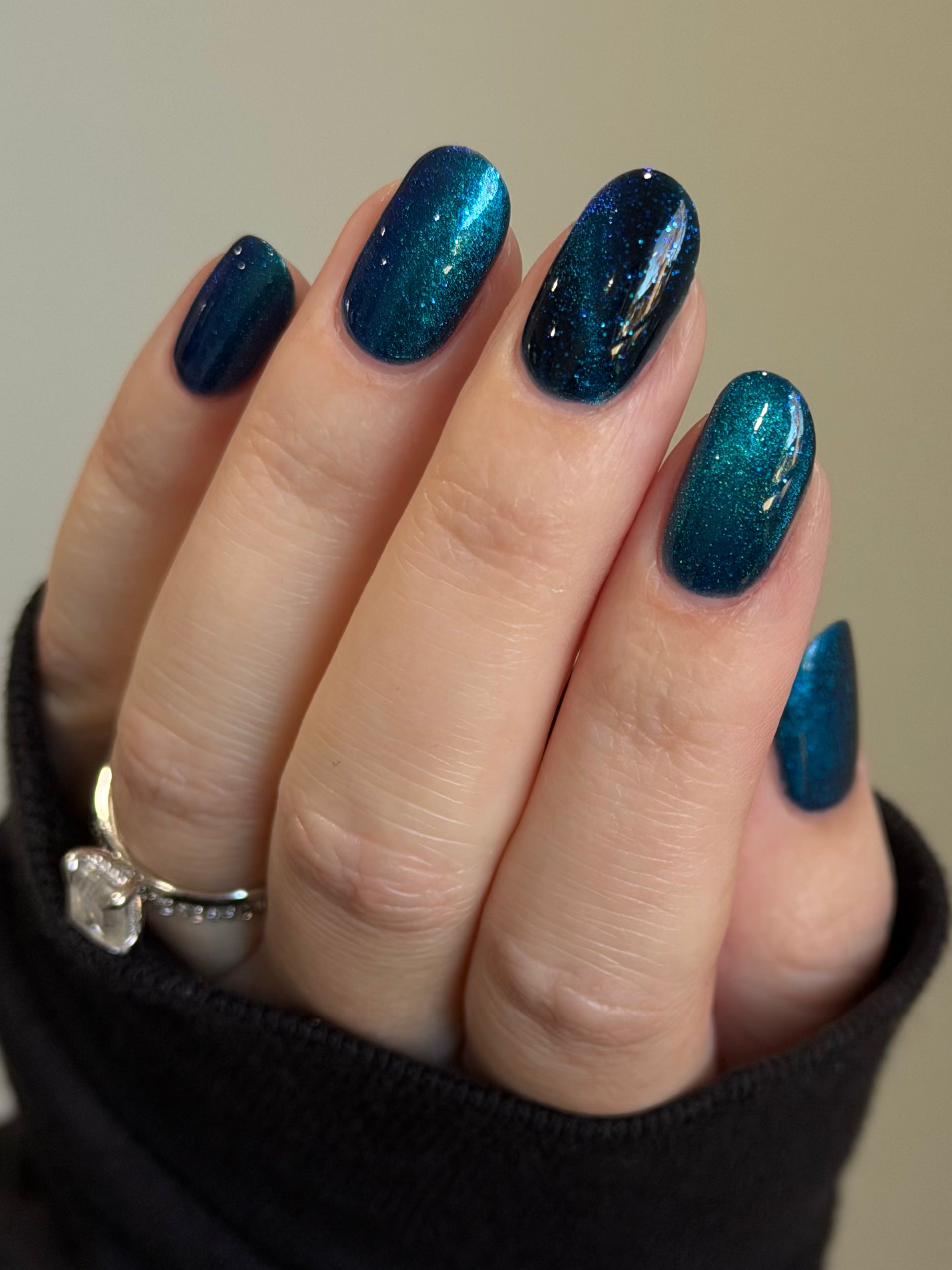Heart of the Ocean by Glitch Lacquer on five oval nails, deep blue magnetic jelly with blue glitters, light skin tone, bright daylight.