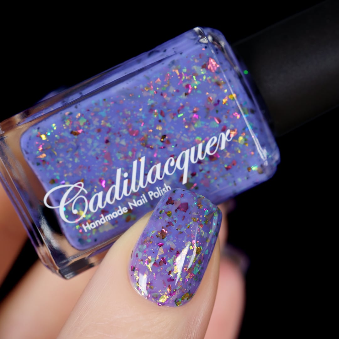 Cadillacquer Don't Worry purple pink chameleon iridescent crelly nail polish, bottle held with one-nail swatch, light skin, studio lighting