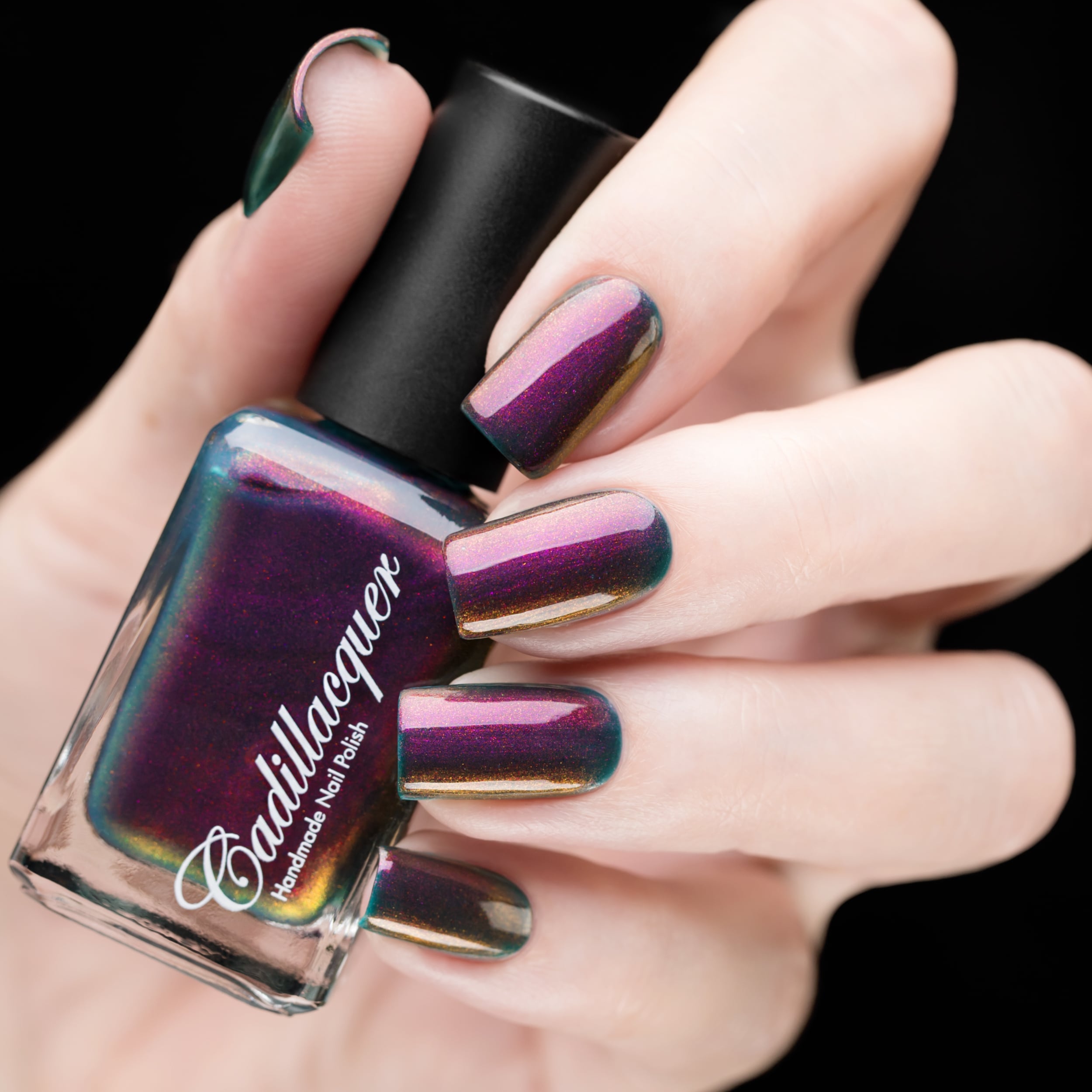 Multichrome shimmer Cadillacquer nail polish in Fear What You Will Become, shown in bottle held in hand with five swatched squoval nails, shifting from deep burgundy-plum through magenta and amber-bronze to dark teal at edges, light skin tone, studio lighting, swatched by @rafinails