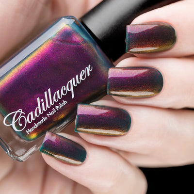Multichrome shimmer Cadillacquer nail polish in Fear What You Will Become, shown in bottle held in hand alongside five swatched squoval nails, shifting from dark murky teal through deep magenta-plum to bronze-amber and orange depending on angle, packed with red-orange and magenta shimmer flash, on light skin tone, studio lighting, swatched by @rafinails
