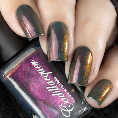 Multichrome shimmer Cadillacquer nail polish in Fear What You Will Become, shown as a swatch on four square nails alongside the bottle, nails shift from murky teal-olive through bronze and warm amber to magenta-rose depending on angle, while the bottle face reads deep magenta-purple with orange shimmer, light skin tone, studio lighting, swatched by @serpentine13