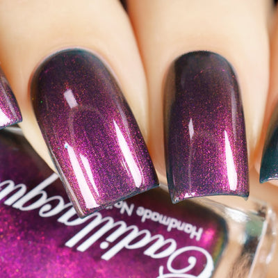 Holographic shimmer Cadillacquer nail polish in Fear What You Will Become, shown swatched on four short natural nails with a deep dark teal-purple base densely packed with magenta and orange holographic shimmer, light skin tone, studio lighting, swatched by @yyulia_m