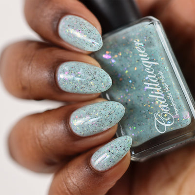 Cadillacquer Fresh Sheets pastel mint iridescent crelly nail polish, bottle held with four-nail swatch, rich skin, studio lighting