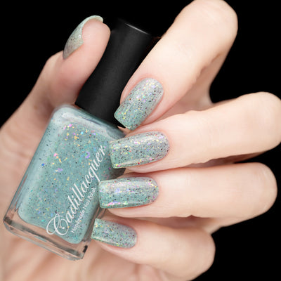 Cadillacquer Fresh Sheets pastel mint iridescent crelly nail polish, bottle held with five-nail swatch, light skin, studio lighting