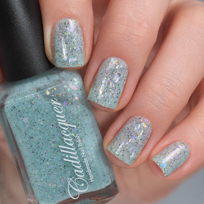 Cadillacquer Fresh Sheets pastel mint iridescent crelly nail polish, bottle held with four-nail swatch, light skin, studio lighting
