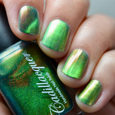 Magnetic multichrome shimmer Cadillacquer nail polish in I Found A Place, shown on five short square nails with a visible diagonal lime green magnetic band over a deep forest green base, with vivid red-to-orange aurora shimmer flash, alongside the Cadillacquer bottle showing deep teal-green with scattered red-orange shimmer, light-medium skin tone, studio lighting, swatched by @caitlinswatches