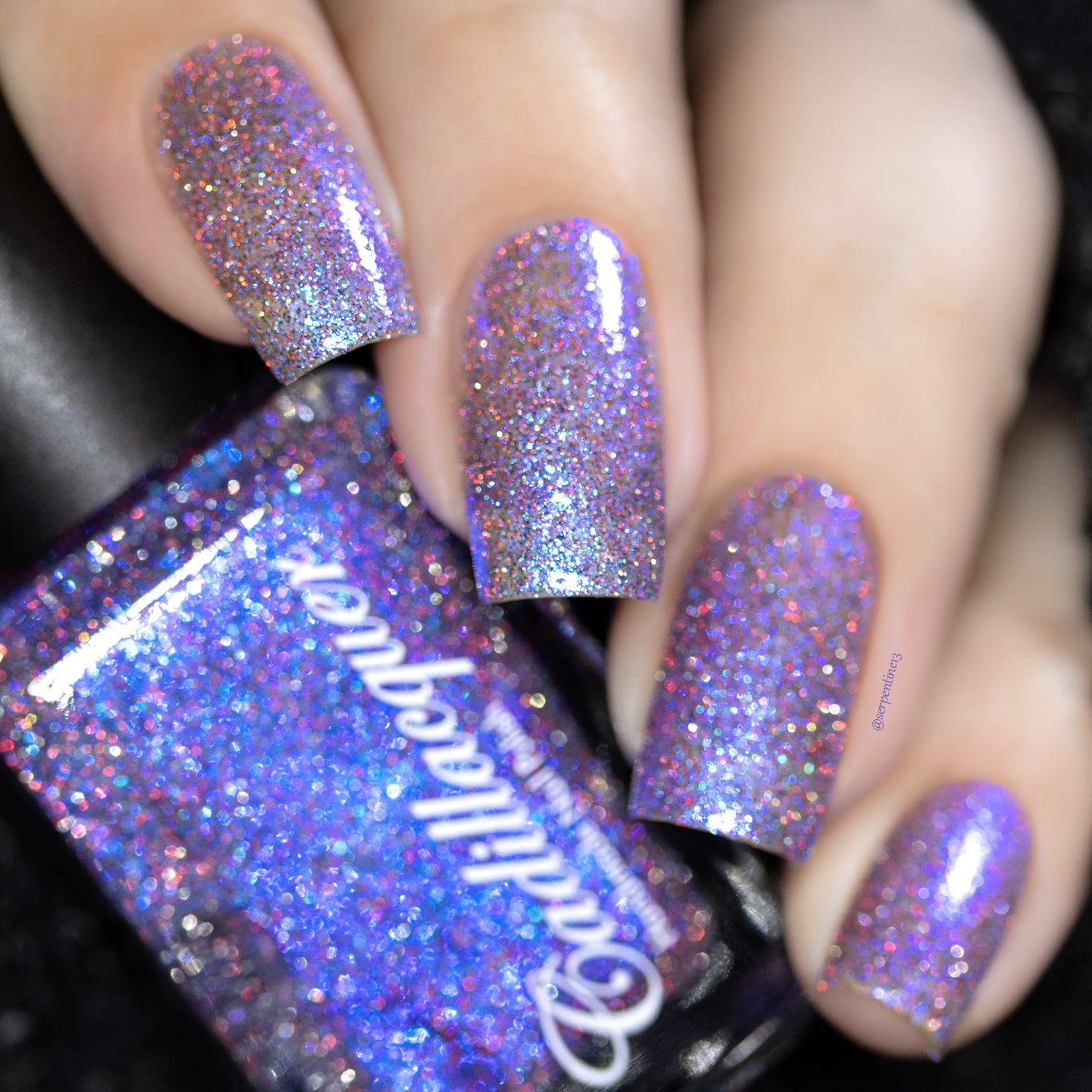 Holographic shimmer glitter Cadillacquer nail polish in I'll Be Right Back, shown on four short square nails and in the bottle, packed with blue micro flakes, violet-periwinkle shimmer, silver holographic micro glitter and red reflective sparks over a sheer base, light-medium skin tone, direct flash lighting, swatched by @serpentine13
