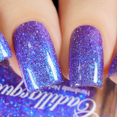 Holographic shimmer and micro-flake Cadillacquer nail polish in I'll Be Right Back, shown on five square-shaped nails packed with bright blue iridescent micro flakes, blue shimmer, and red and charcoal reflective glitter sparks over a sheer violet-blue base, light skin tone, direct flash lighting, swatched by @yyulia_m