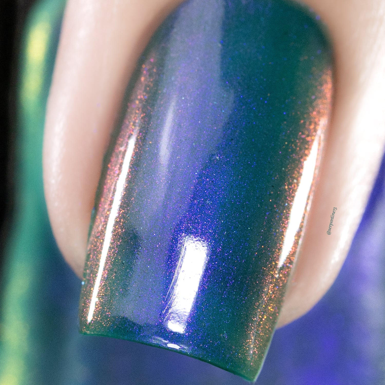 Multichrome holographic shimmer Cadillacquer nail polish in It's All For You, extreme macro closeup of a single square nail showing a deep teal-green base shifting to violet-purple with dense copper-orange holographic shimmer particles, on light skin tone, studio lighting, swatched by @serpentine13