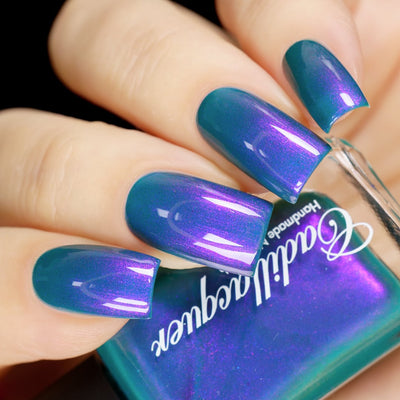 Multichrome shimmer Cadillacquer nail polish in It's All For You, swatched on eight square nails held alongside the bottle, showing a teal-green base that shifts through blue-teal to vivid violet-purple shimmer at angled light, light skin tone, studio lighting, swatched by @yyulia_m